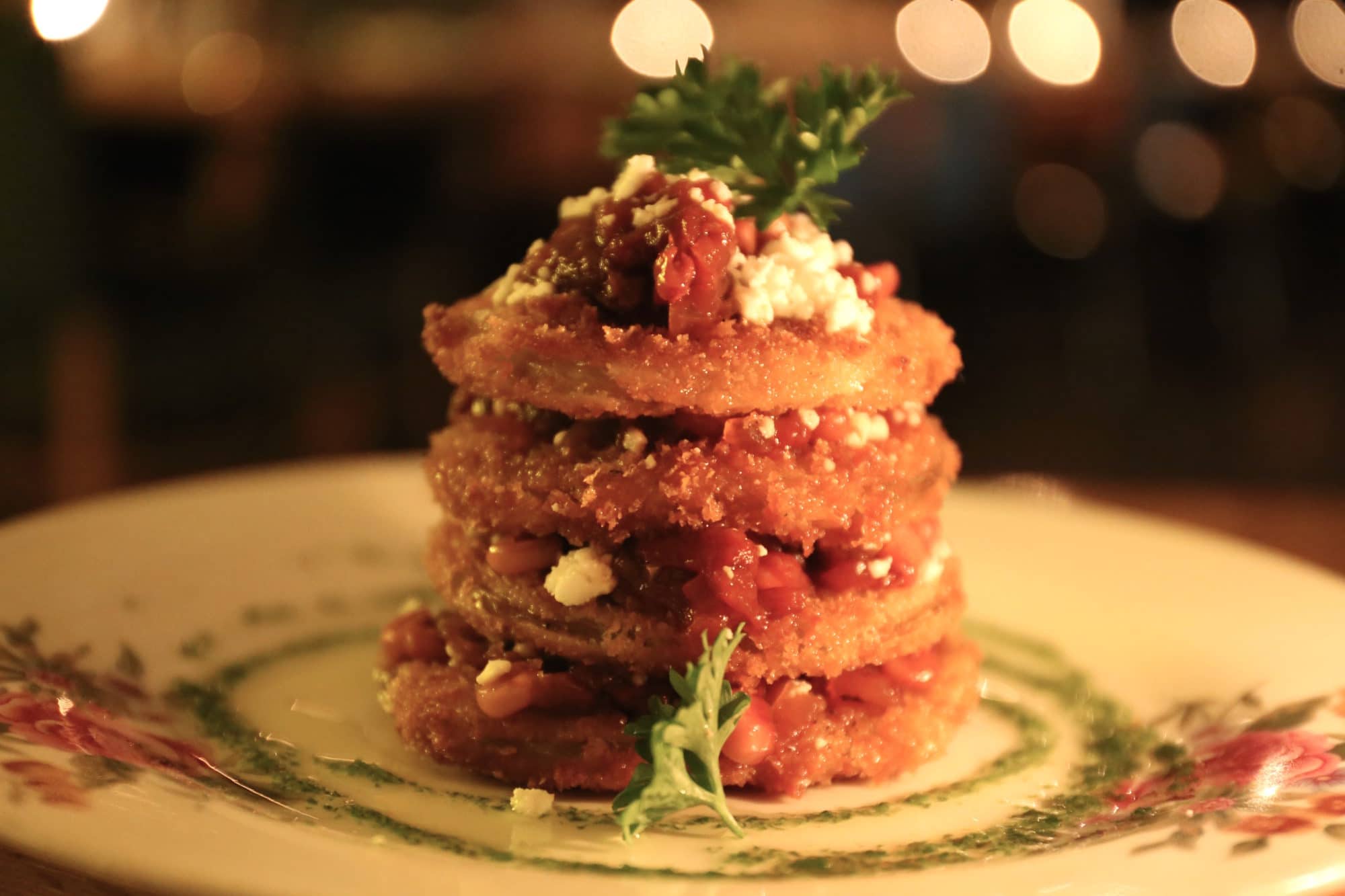 A tower of breaded green tomatoes with feta, roasted red peppers and corn chutney.
