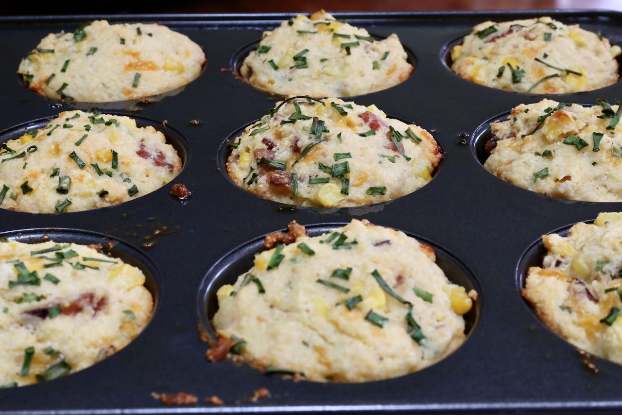 Perfectly browned muffins out of the oven feature sliced chives on top.