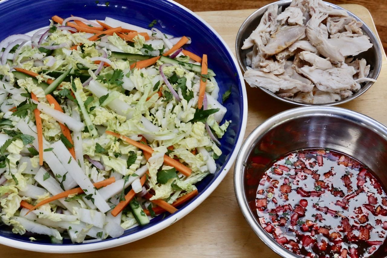 Prepare chopped vegetables, vinaigrette and shredded roast chicken in separate mixing bowls.