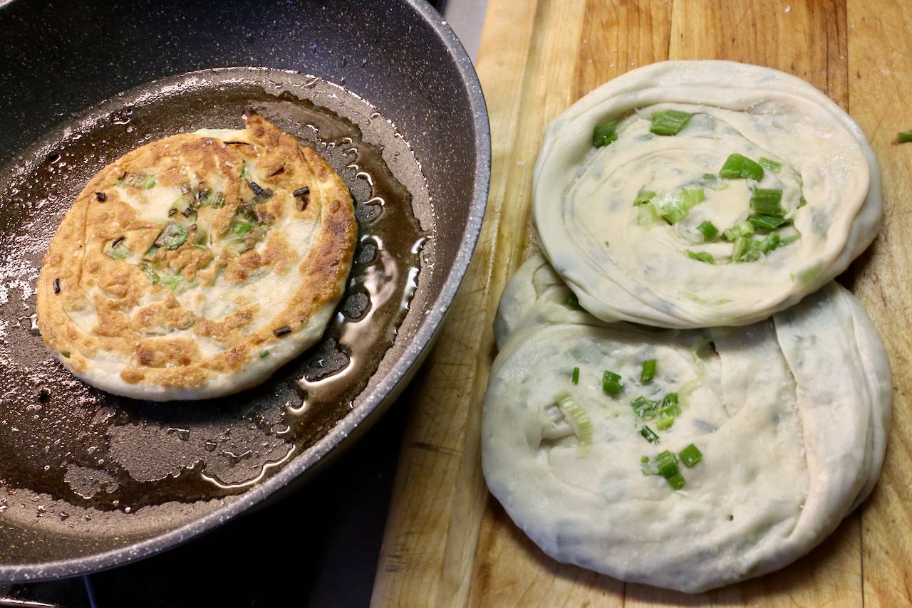 Flip scallion pancakes after frying in oil for 2-3 minutes until golden brown.