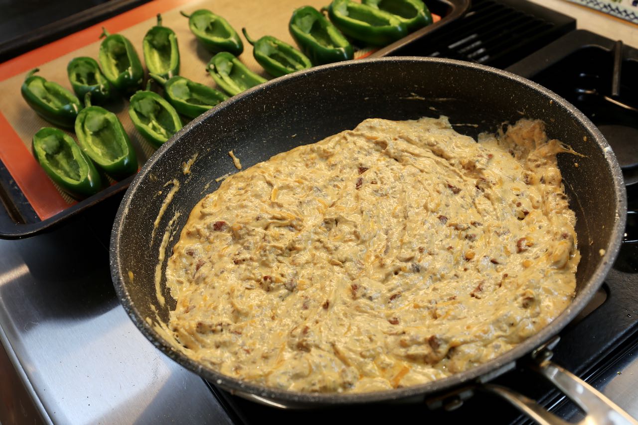 Melt cheesy chorizo filling in a skillet until well combined then scoop into jalapeno pepper boats.