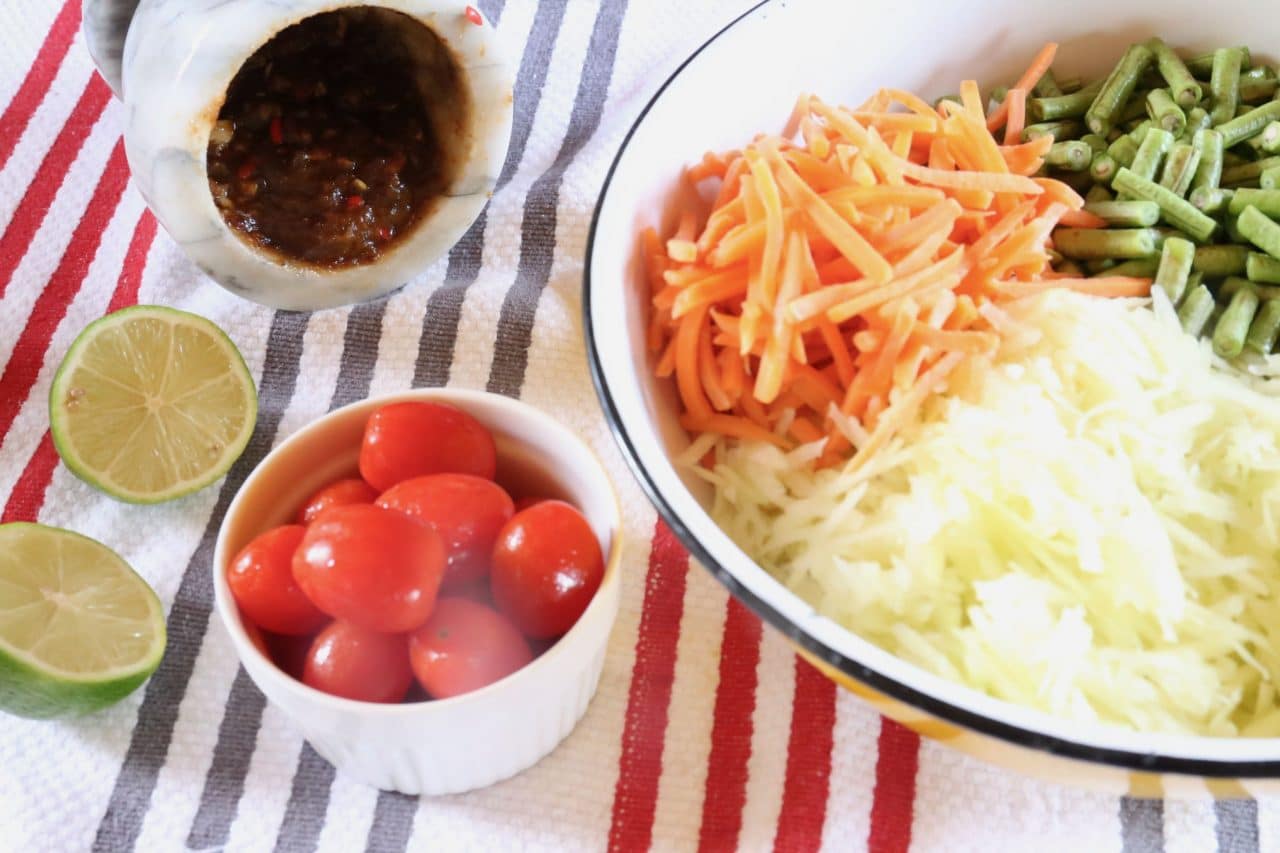 Combine vegetables with Laos Papaya Salad paste in a large mixing bowl with lime juice.