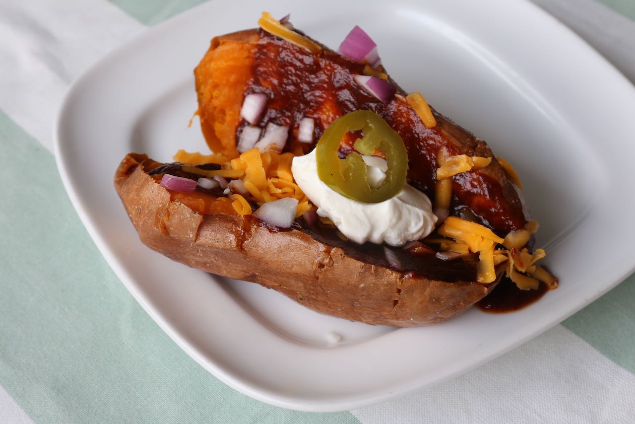 BBQ baked sweet potatoes topped with barbecue sauce, cheddar, sour cream, red onion and pickled jalapeno.