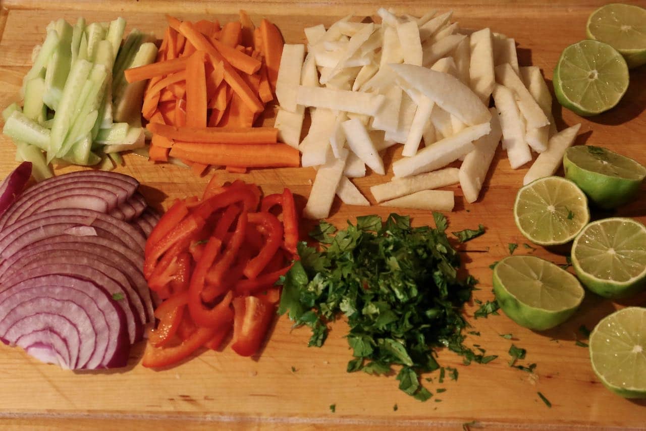 Start making this easy Singapore Salad by slicing fresh vegetables and herbs.