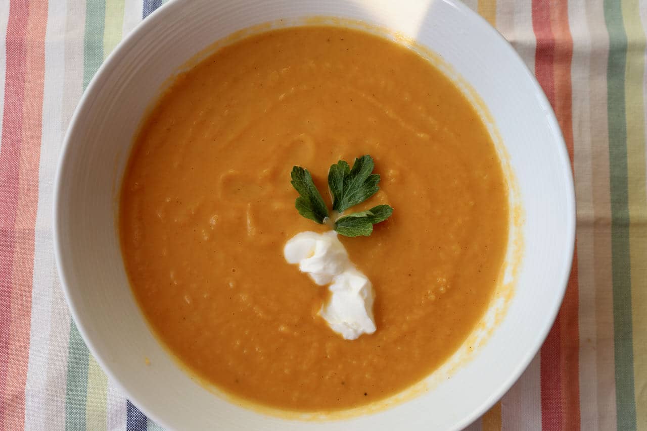 Serve Pumpkin and Sweet Potato Soup with sour cream and parsley.