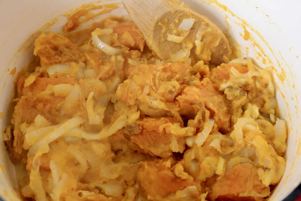 Use a wooden spoon to stir onions, sweet potato and pumpkin.