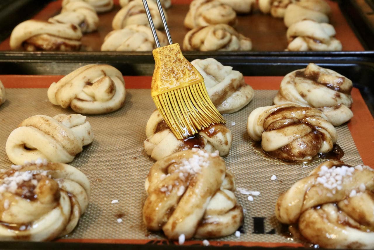 Use a pastry brush to slather Kardemummabullar with cinnamon cardamom glaze.