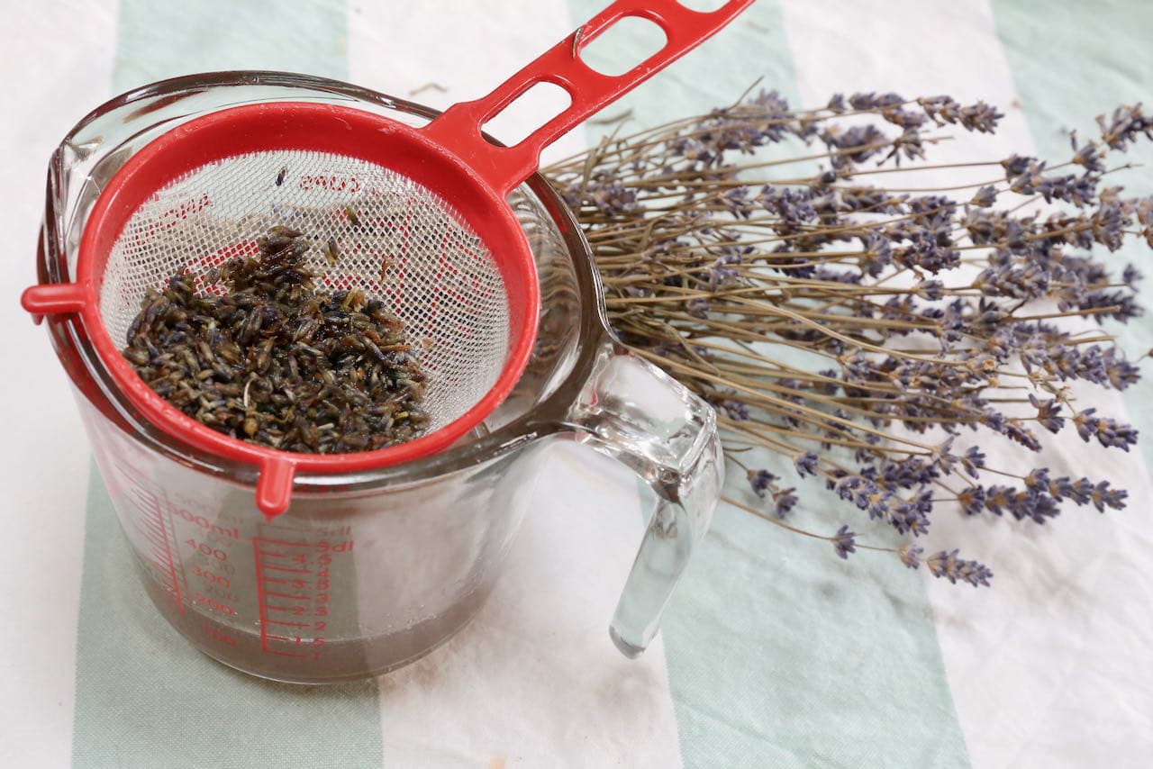 Prepare homemade lavender simple syrup then strain the liquid through a sieve.
