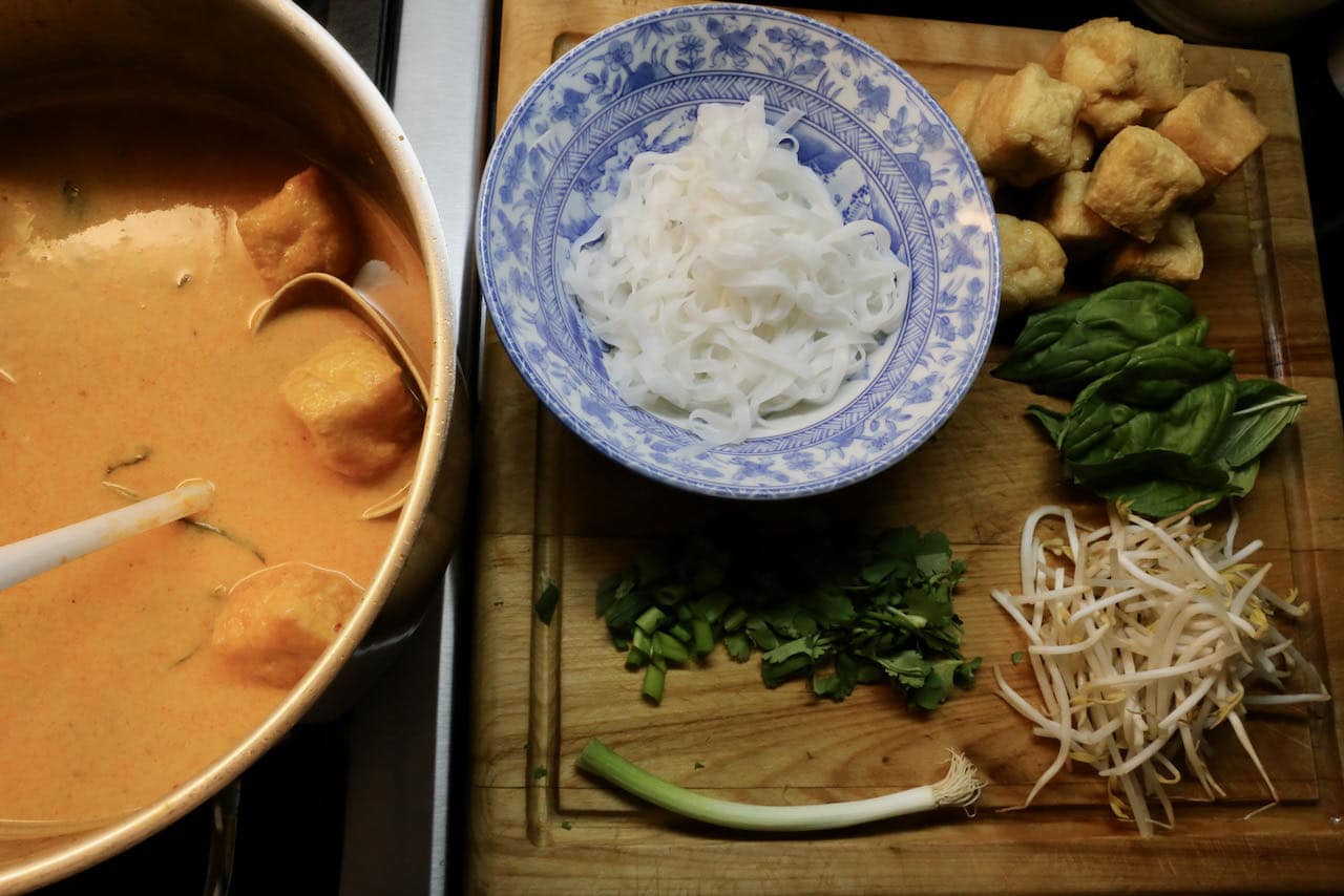 Assemble Singaporean Soup Seafood Laksa in large bowls featuring rice noodles, bean sprouts, fried tofu and curry sauce.