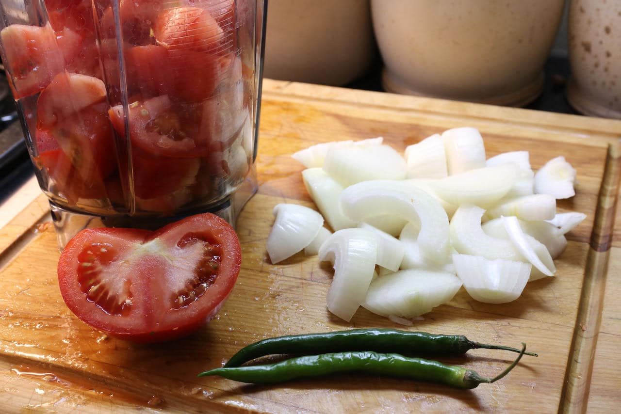 Prepare Chingri Malai Curry sauce by filling a blender with tomato, onion and green chili.