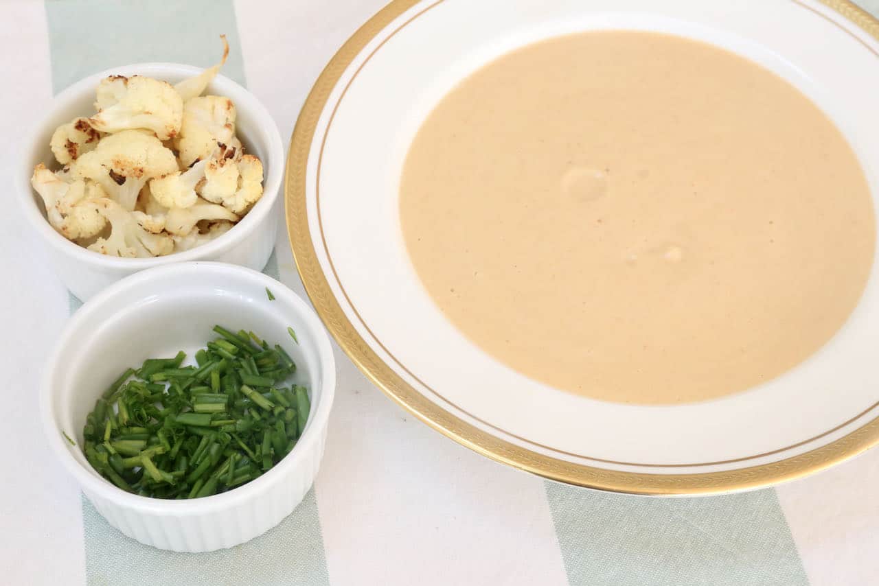 This easy homemade Vegan Cauliflower Soup recipe is garnished with chopped chives and roasted cauliflower florets.
