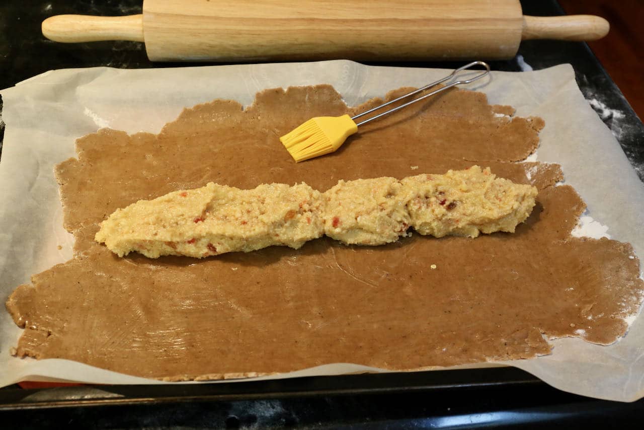 Wash Gevulde Speculaas dough with egg and create a log with almond cherry filling.