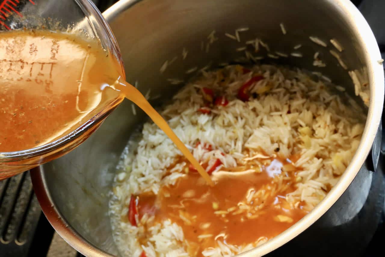 Pour tomato paste and water into the pot with rice and cook covered.