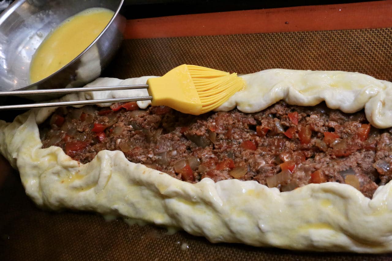 Paint Kiymali Pide crust with egg wash using a pastry brush.