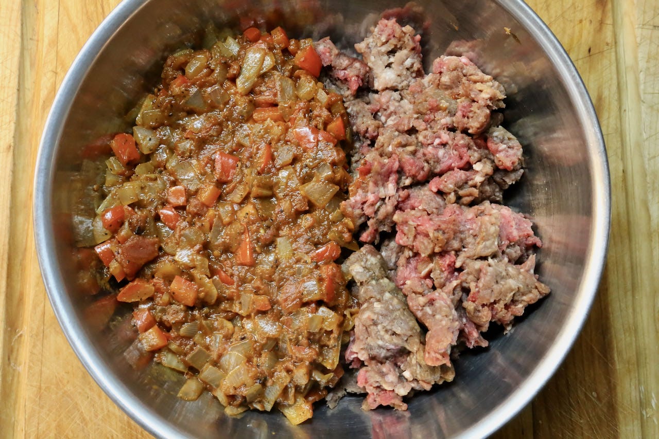 In a mixing bowl combine minced beef and sauteed vegetables with your hands.