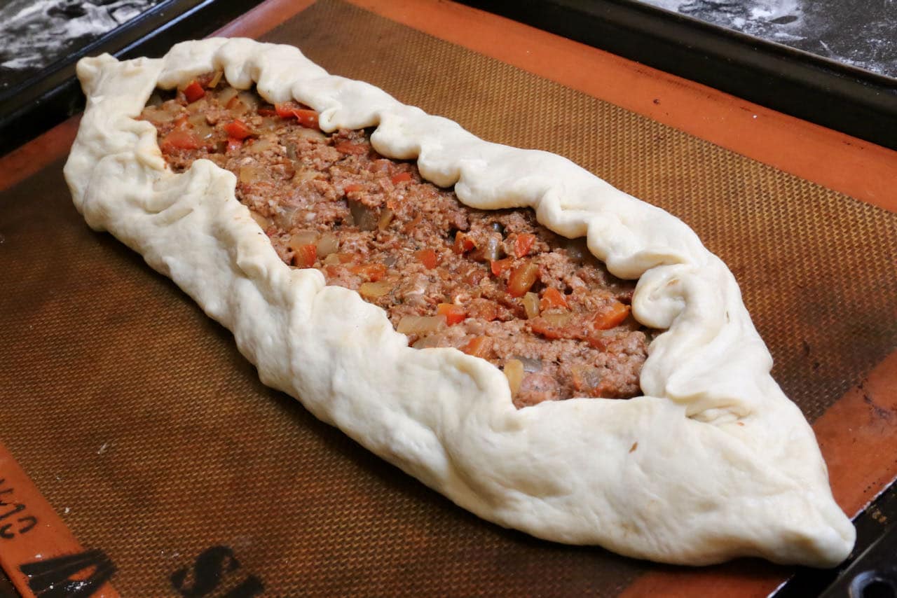 Fold Kiymali Pide dough inwards to create a 1-inch crust.