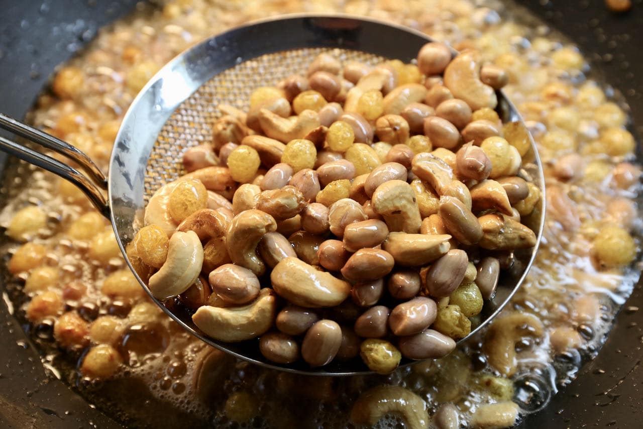 After frying the moong dal add raisins, cashews and peanuts to the hot oil.
