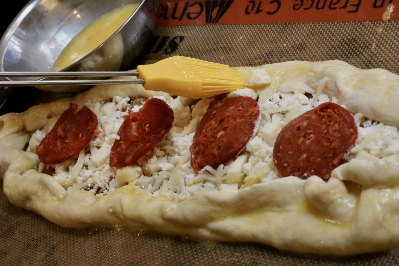 Paint Peynirli Pide crust with egg wash using a pastry brush.