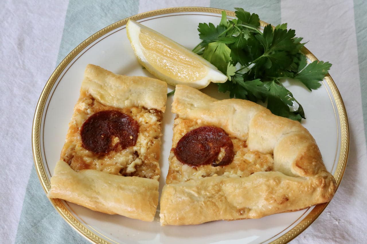 Serve Peynirli Pide with lemon wedge and fresh parsley.