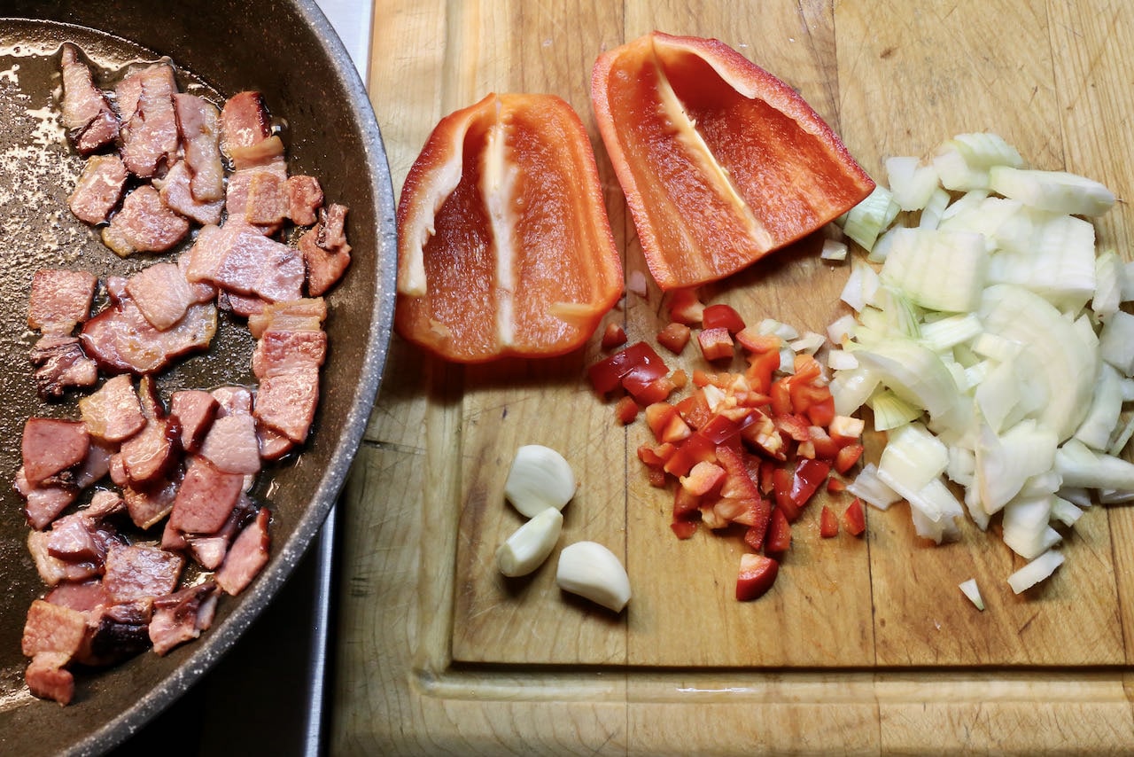 Fry bacon in a skillet and chop bell pepper, onion and garlic.