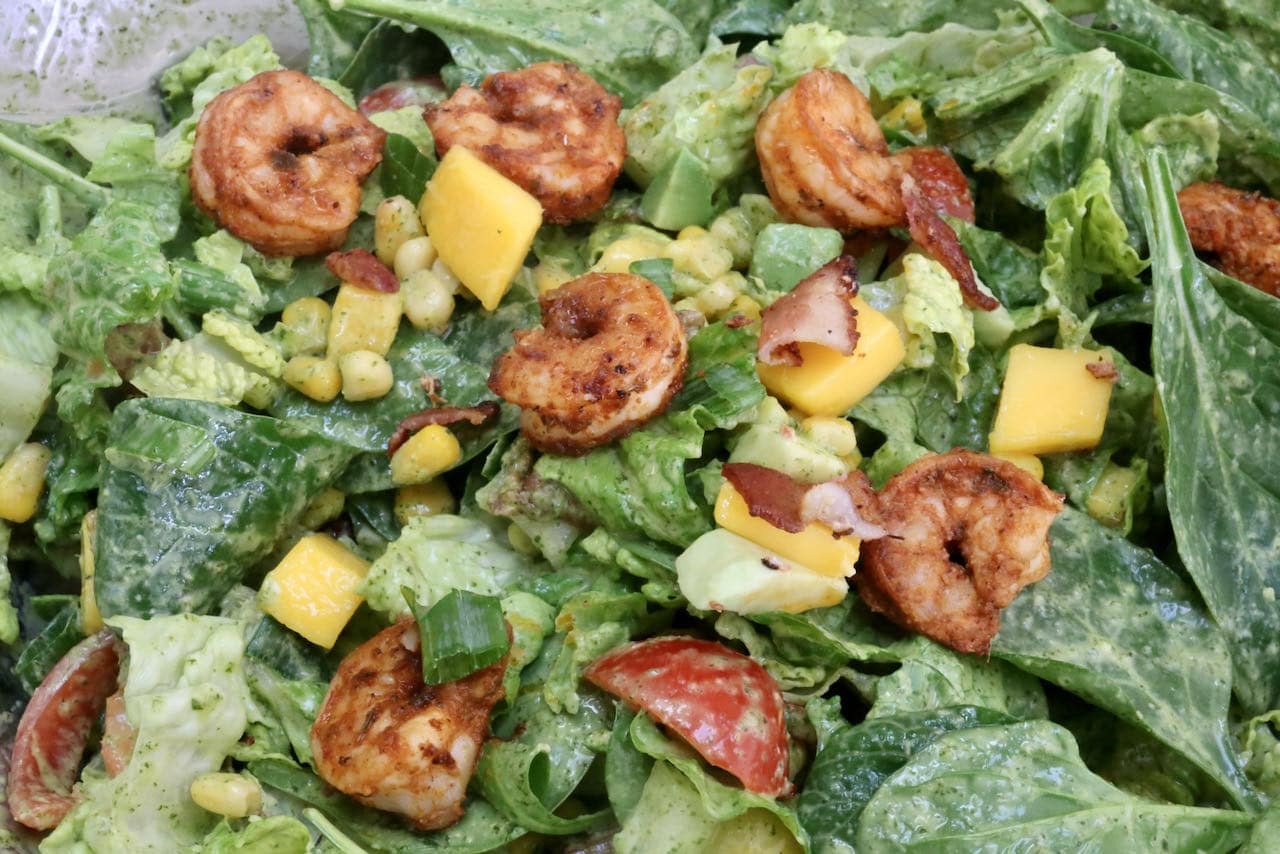 Toss salad in dressing then top with Cajun shrimp, crispy bacon and mango chunks.