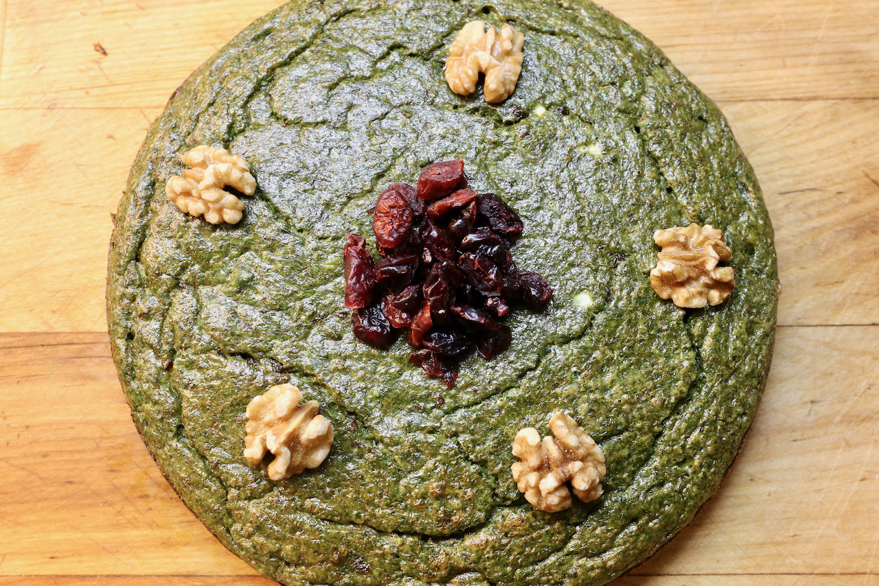 Decorate Kookoo Sabzi with dried cranberries and walnuts.