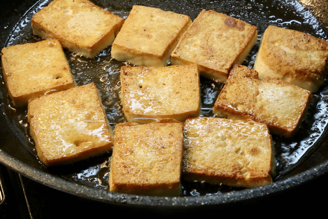 Pan fry slices of tofu in a nonstick skillet until golden brown and crispy. 
