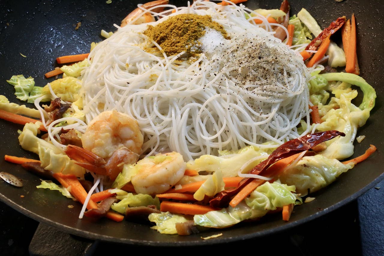 Toss Singapore Chow Mei Fun ingredients with vermicelli, curry powder and pepper.