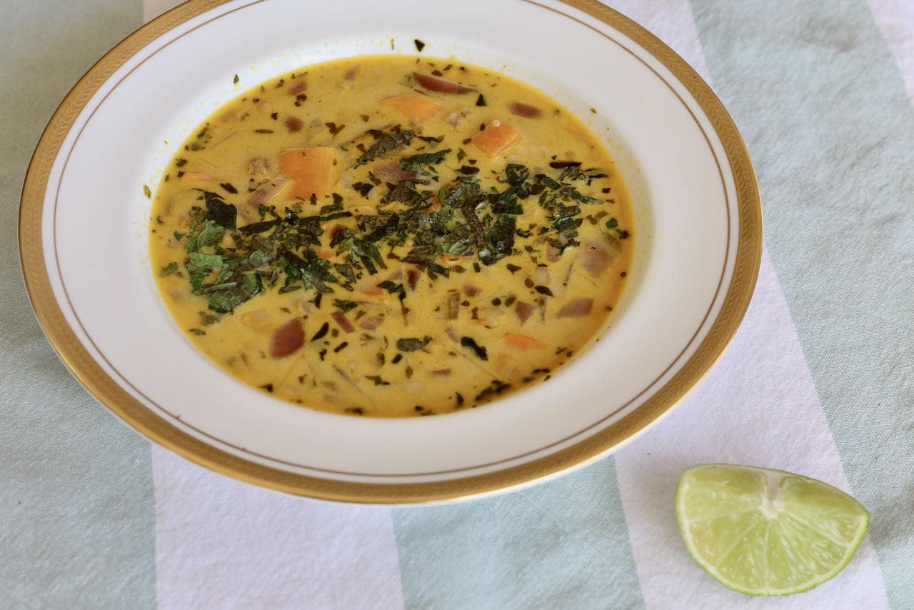 Serve Chupe de Quinoa topped with chopped fresh mint and lime wedge.
