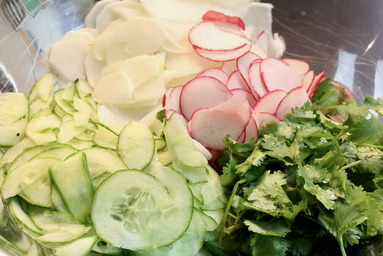 In a large mixing bowl toss sliced cucumber, daikon, radish and cilantro.