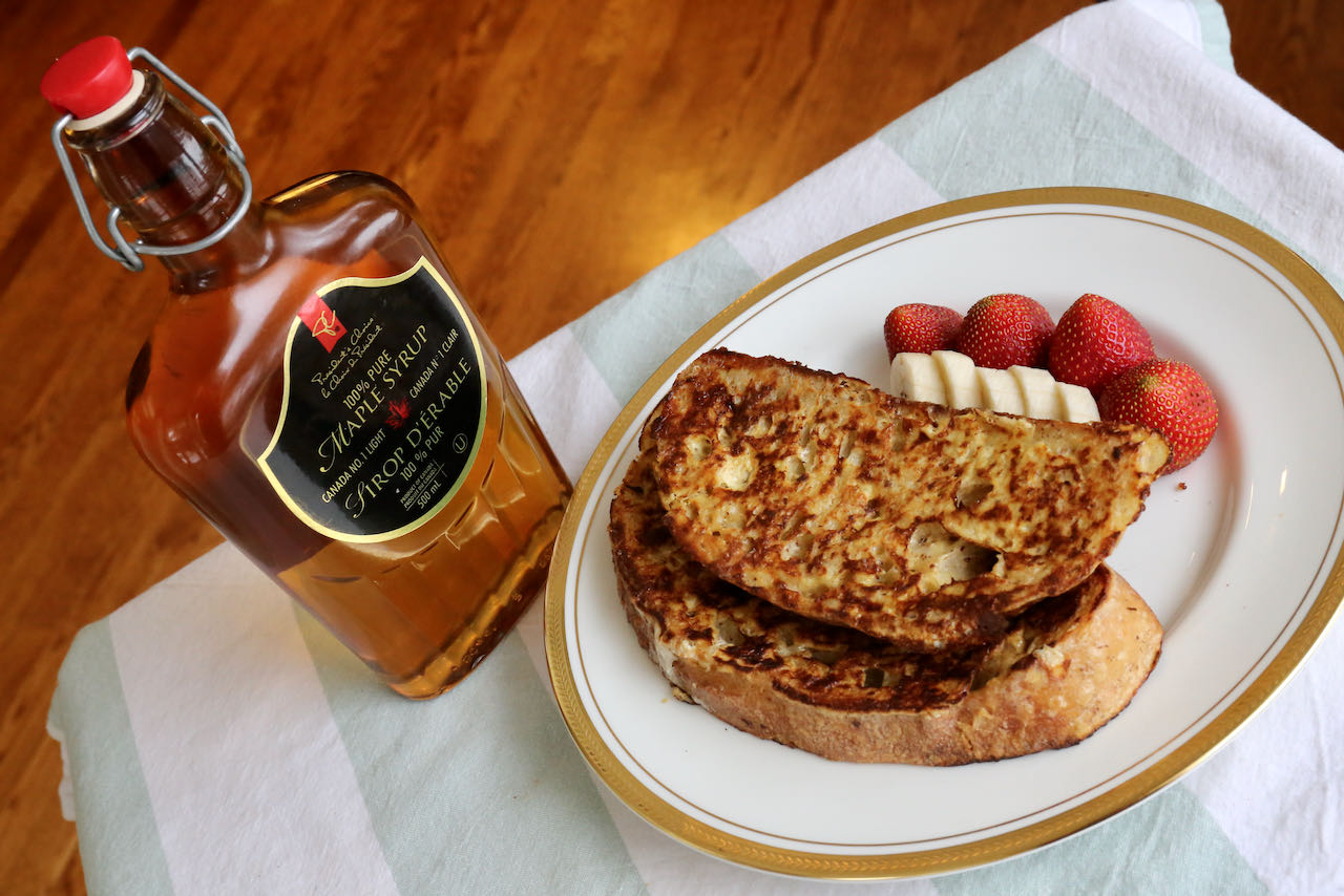 Serve Sourdough French Toast with maple syrup, banana slices and strawberries.