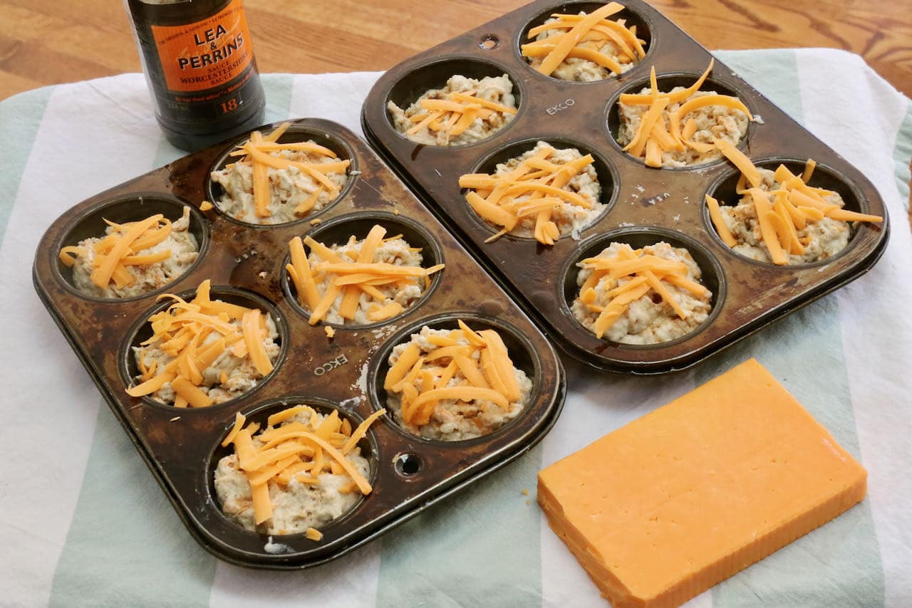 Garnish Welsh Rarebit Muffins with shredded cheese and Worcestershire before baking.