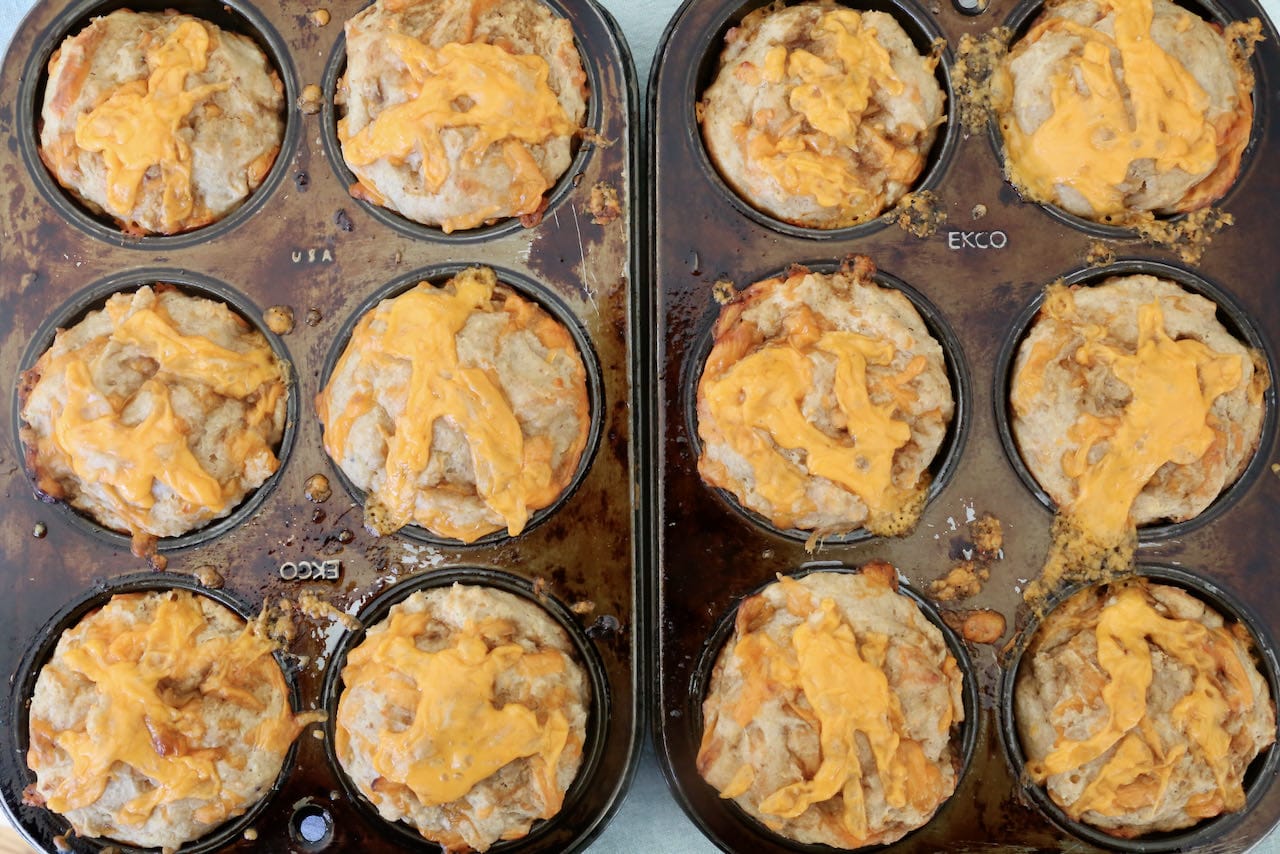Savoury Welsh Rarebit Muffins are topped with melted cheddar cheese.