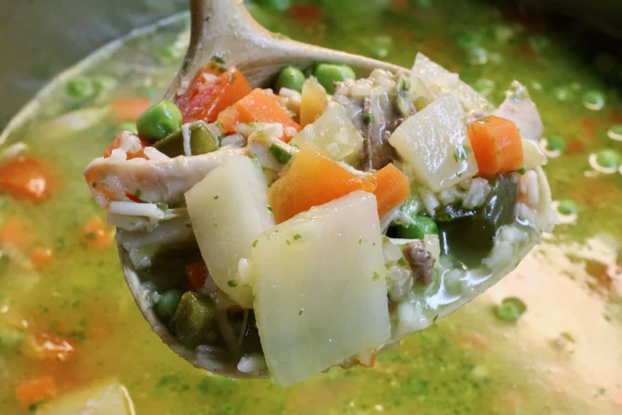 Use a ladle to serve Aguadito de Pollo into bowls.