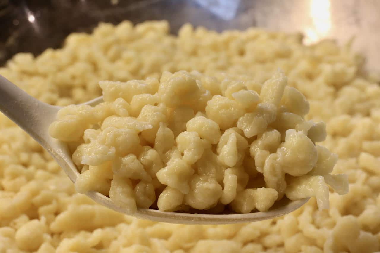 Scoop German noodles into a casserole dish to assemble Schwäbische Käsespätzle.