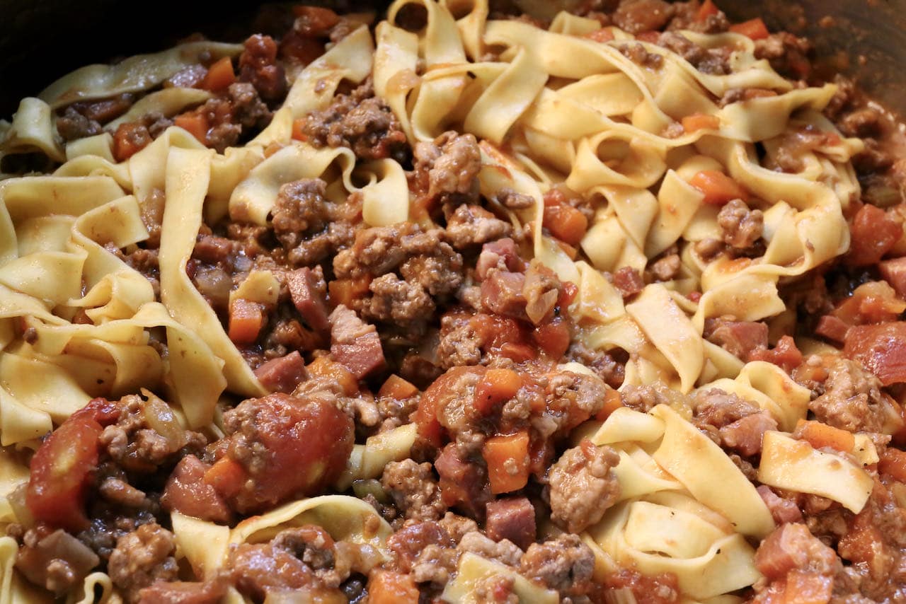 Toss al dente tagliatelle pasta noodles in the bolognese sauce. 