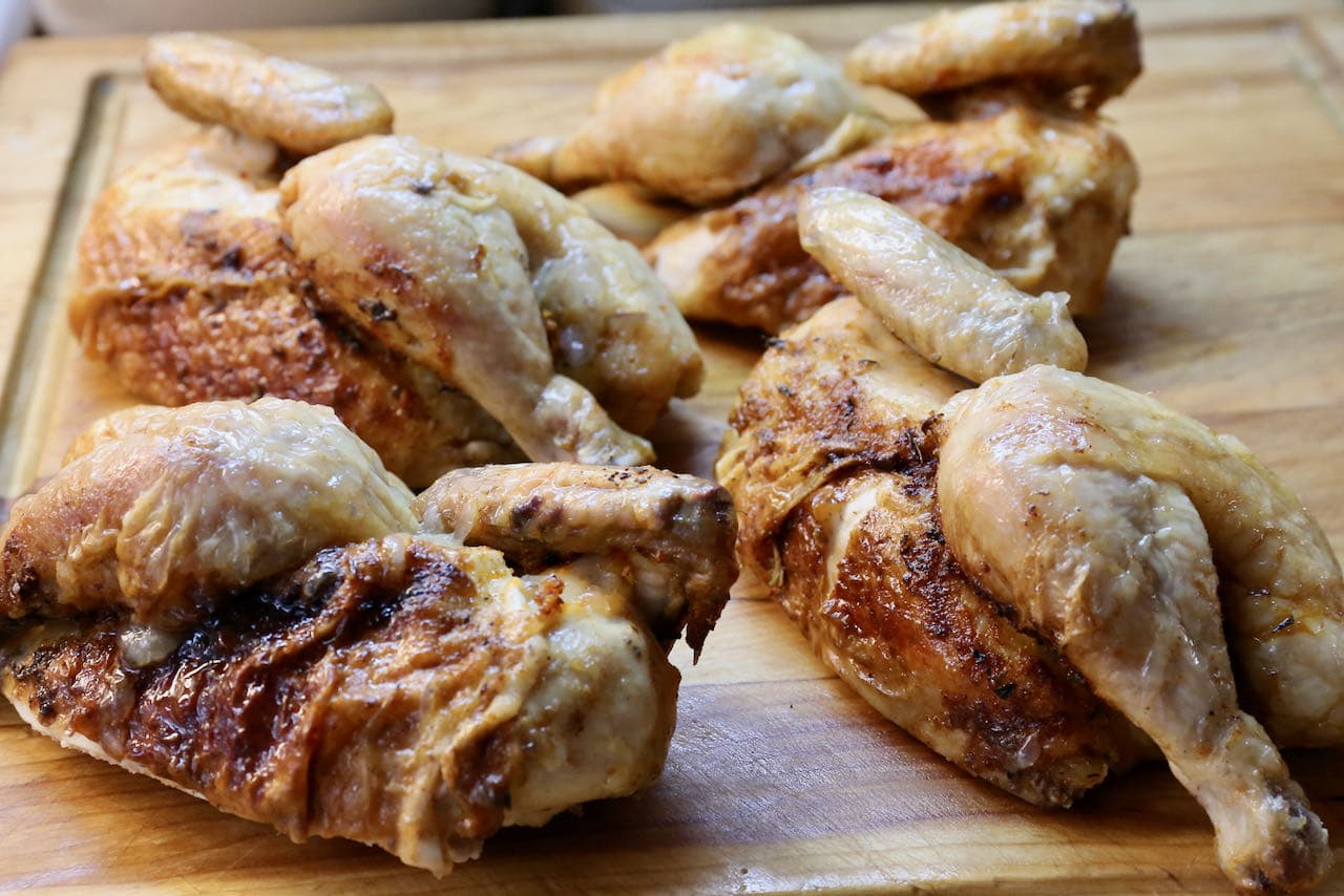 Divide Air Fried Cornish Hen into quarters using a sharp French knife on a cutting board.
