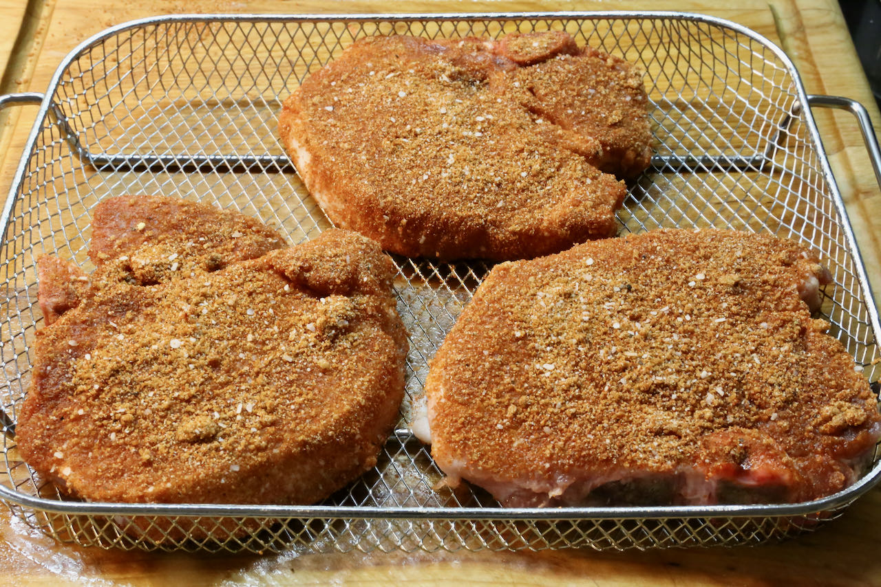 Place seasoned bone in pork chops into air fryer basket.