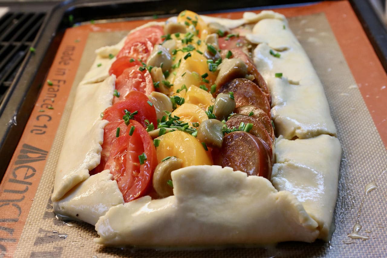 Fold the French Tomato Tart pastry onto itself and organize the tomato slices into colourful rows before baking.