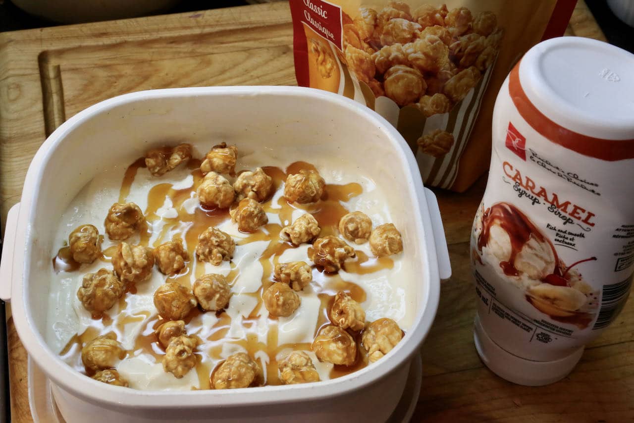 Pour churned popcorn ice cream into a tub and top with caramel corn and caramel drizzle.