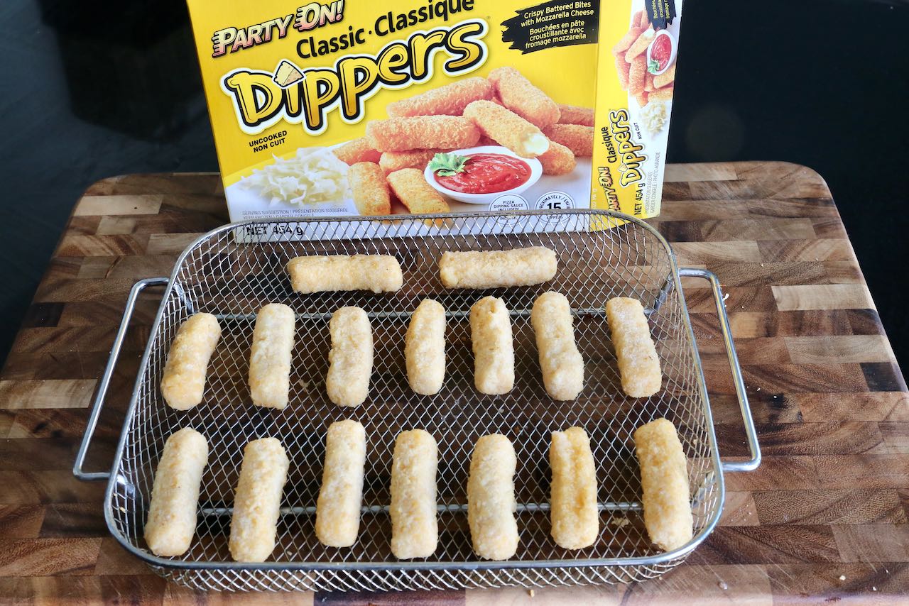 Frozen Mozzarella Cheese Sticks in an Air Fryer basket.