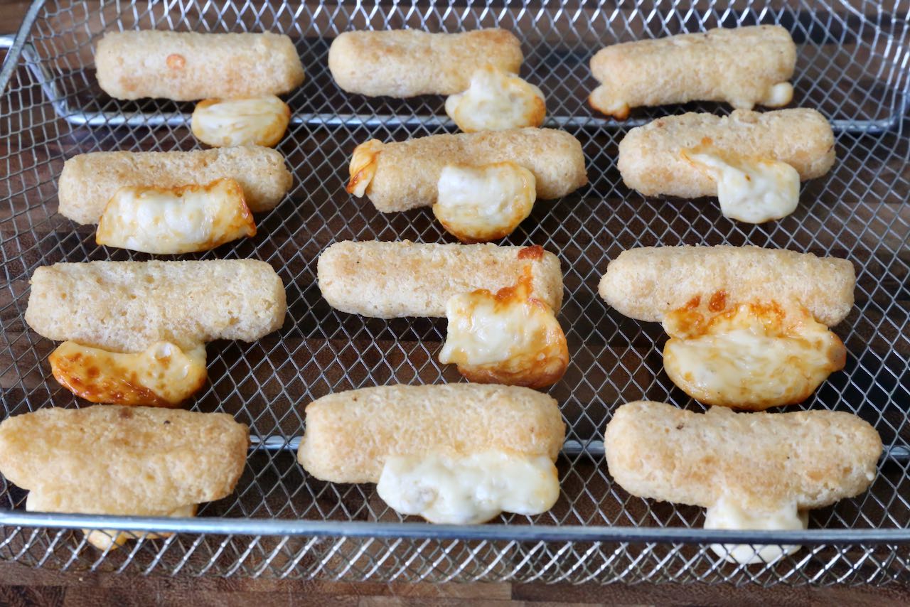 Melted cheese oozing out of Frozen Mozzarella Sticks cooked in an air fryer.