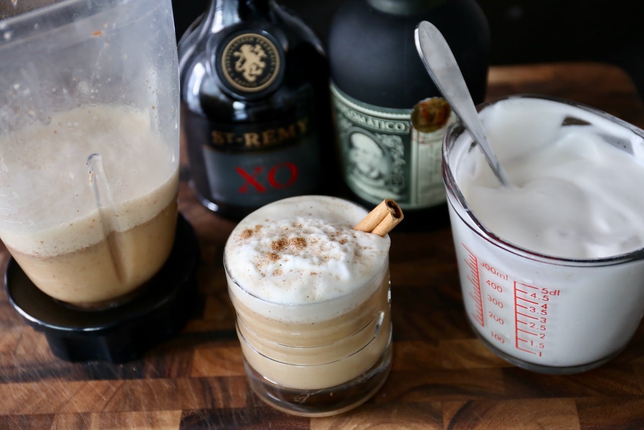 Serve Vegan Eggnog in a cocktail glass with rum brandy mixture and foamy creamy whipped aquafaba.
