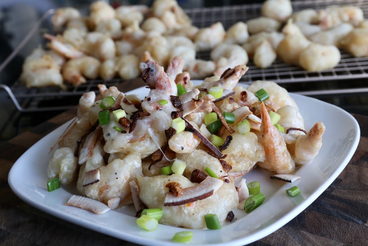 Our homemade Creamy Coconut Shrimp recipe is garnished with scallions and coconut chips.