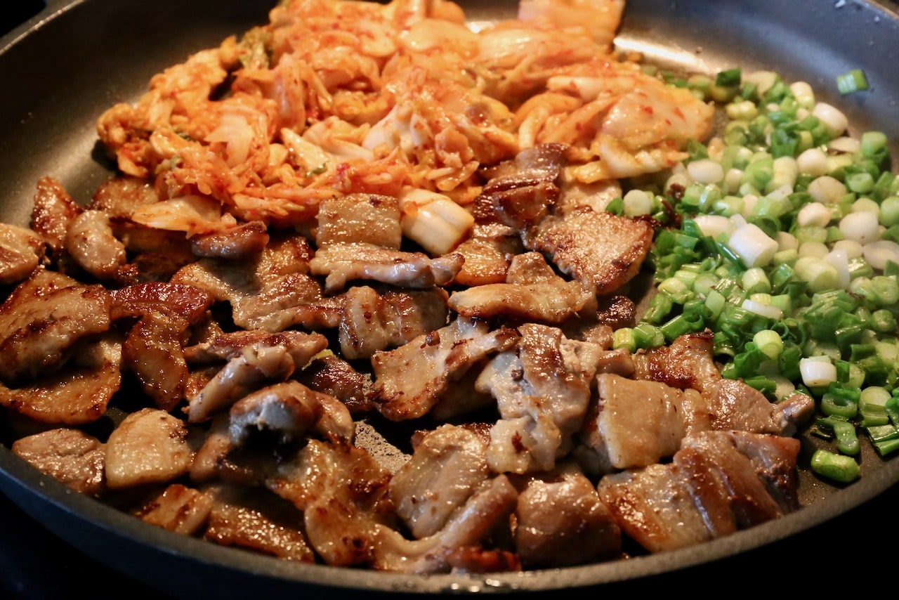 This Kimchi Pork Stir Fry recipe is cooked in a skillet with scallions and Korean fermented spicy cabbage.