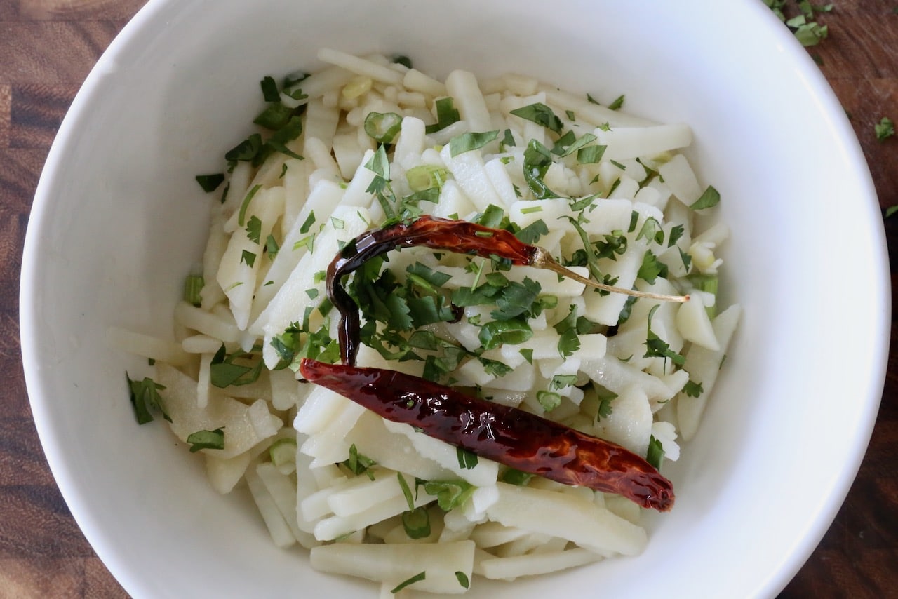 Garnish Chinese Potato Salad with fried dried red chili and chopped cilantro.