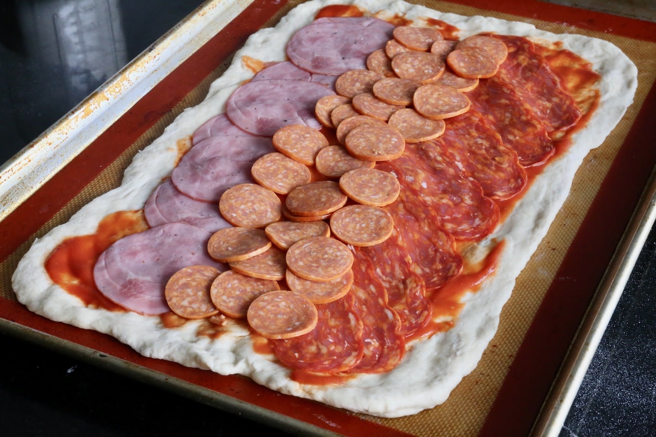 Roll the dough into a rectangle, slather with tomato sauce and top with Italian meats.