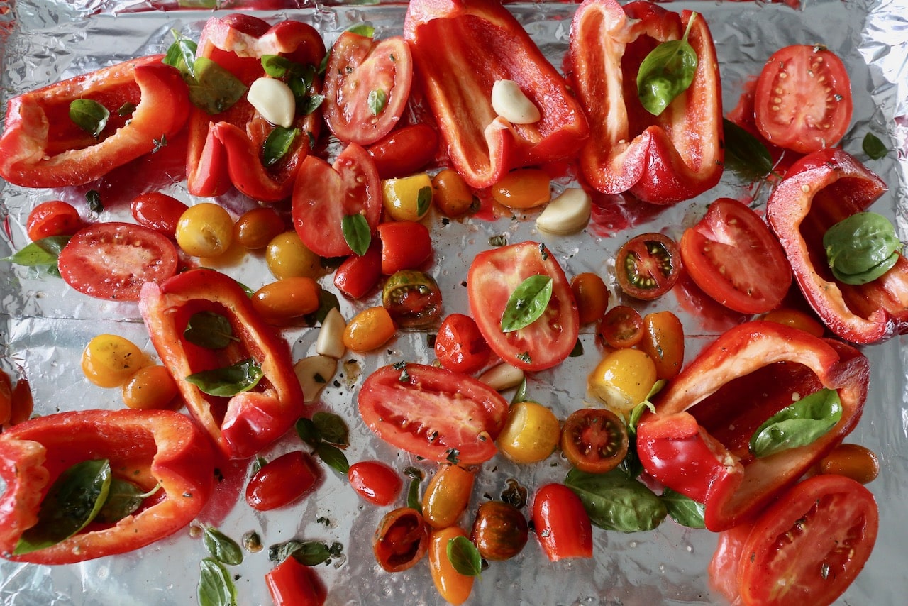 Roast tomatoes and sweet bell peppers with garlic on a baking sheet. 