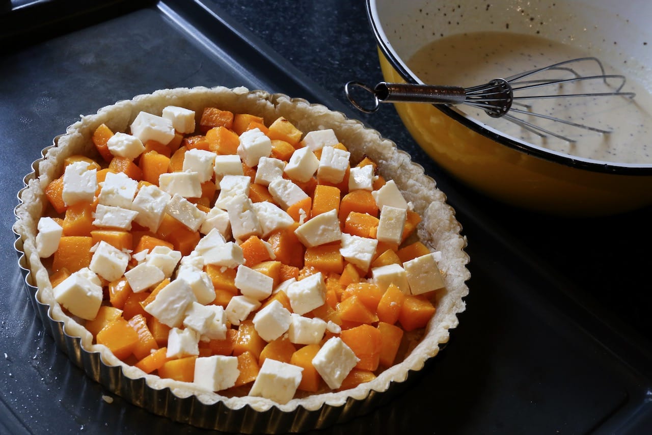 After par-baking the crust fill tart pan with cubes of roasted squash and feta cheese.