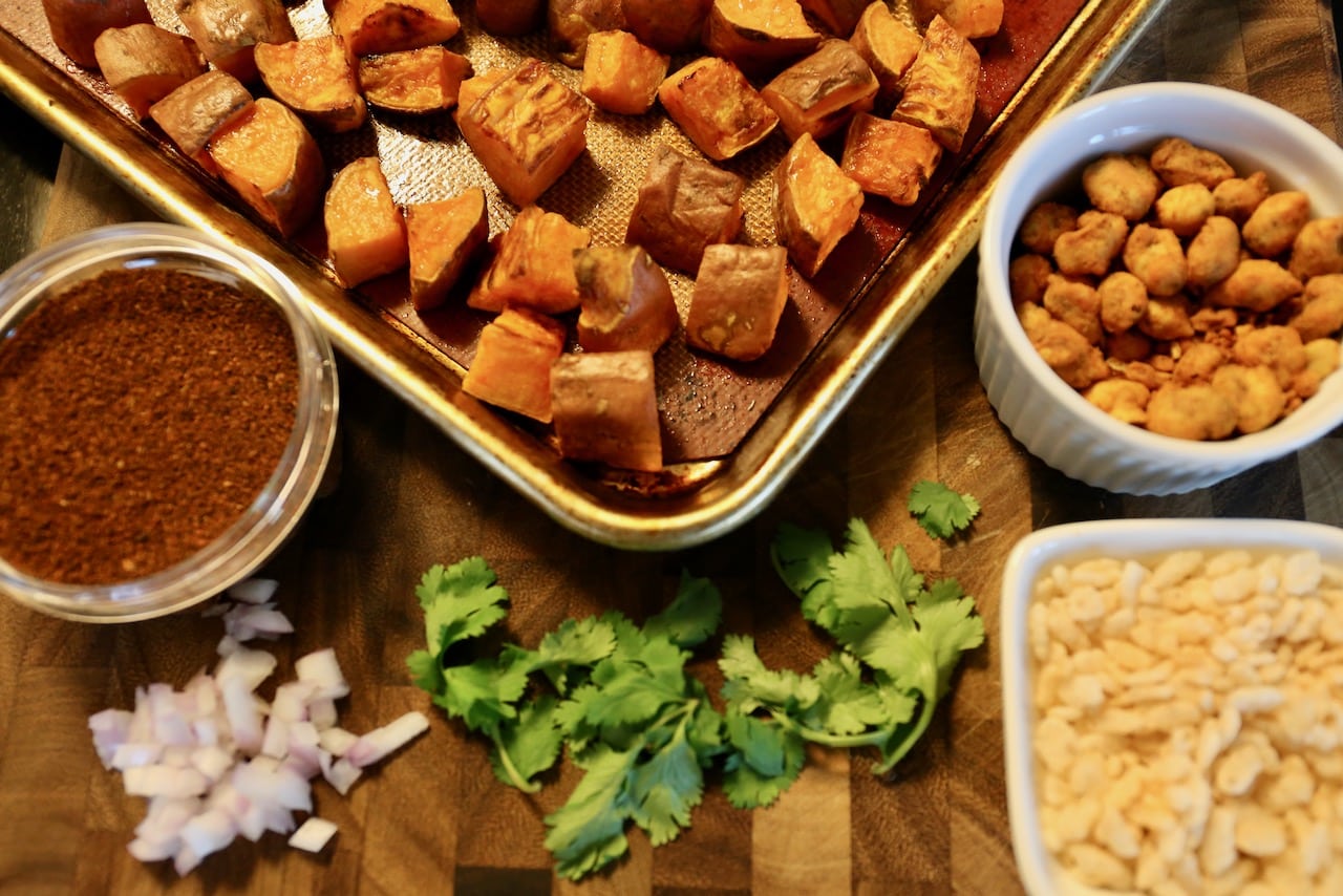 Garnish roasted sweet potato chunks with onion, cilantro, puffed rice and spicy chili powder.